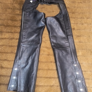 May include: Black leather chaps with a lace-up detail at the waist and snap closures down the sides.