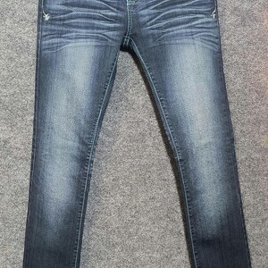 May include: Dark wash denim jeans with decorative stitching and embellishments on the front pockets. The jeans have a classic five-pocket design and a button and zipper closure. The denim is faded in areas for a worn look.