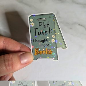 May include: A green and white holographic sticker with the text "Plot Twist: I bought more books".