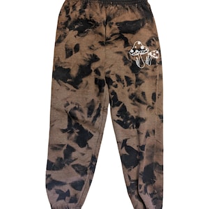 May include: Brown sweatpants with a black tie-dye pattern and a white mushroom graphic on the left leg.