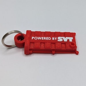 May include: Red plastic keychain shaped like an engine valve cover with the words "POWERED BY SVT" in white lettering.
