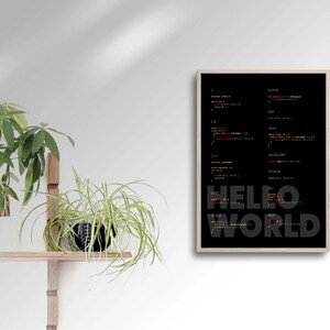 May include: A framed black and white poster with the text "HELLO WORLD" in large, bold letters. The poster features code snippets in various programming languages, including C, C++, Java, Python, and JavaScript.