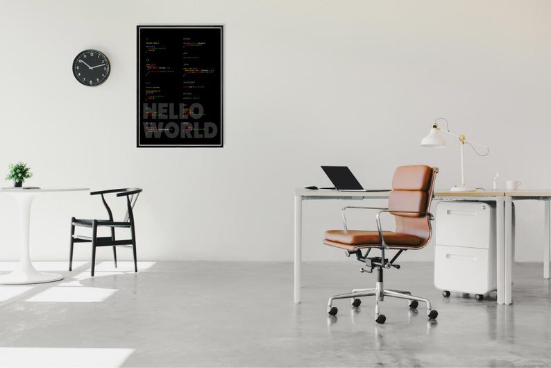 May include: A black and white poster with colorful code and the text "HELLO WORLD" hanging on a white wall in a modern office. A brown leather office chair sits in front of a white desk with a laptop and a lamp.