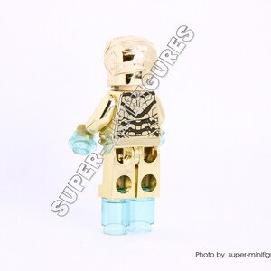 Puede incluir: Minifigura Lego de Iron Man de color dorado con un acabado dorado met&aacute;lico y un dise&ntilde;o negro y plateado en el pecho. La minifigura tiene piernas azules transl&uacute;cidas.