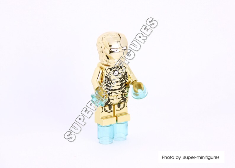 Puede incluir: Minifigura Lego de Iron Man de color dorado con una base azul transl&uacute;cida. La minifigura tiene un traje dorado detallado con detalles negros y una cara roja.