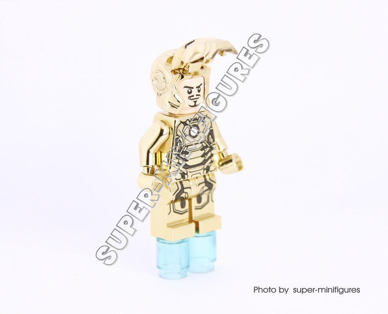 Puede incluir: Minifigura Lego de Iron Man de color dorado con un casco y una armadura dorados con detalles negros. La minifigura est&aacute; de pie sobre una base azul claro.