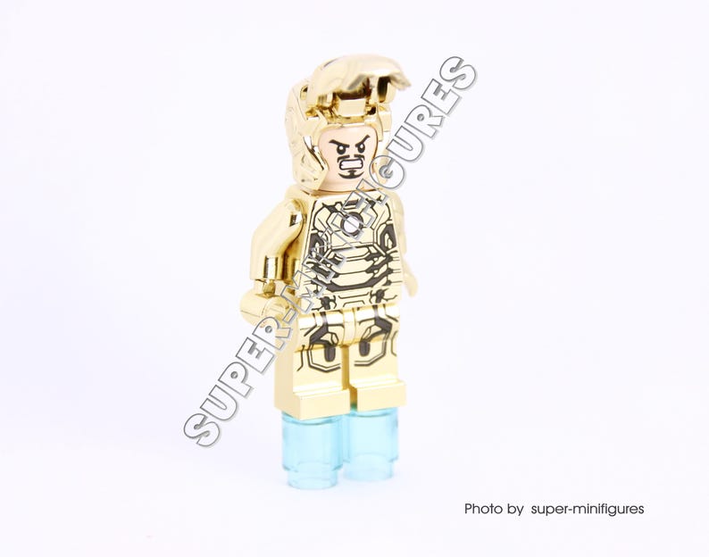 Puede incluir: Minifigura Lego dorada de Iron Man con un casco y una armadura dorados. La minifigura tiene un dise&ntilde;o negro y dorado en la armadura y una base azul transl&uacute;cida.