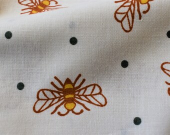 May include: White fabric with a repeating pattern of brown bees and black dots. The bees have yellow stripes and brown wings.