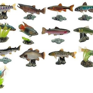 May include: A selection of fish ornaments, each displayed on a small rock base. The fish showcase diverse colours and patterns, including browns, greens, and oranges, with some sporting spots or stripes. These figurines are likely intended for decorative use.