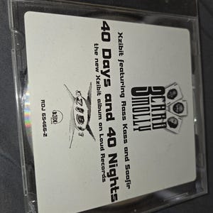 May include: A CD case featuring the album "40 Days and 40 Nights" by Xzibit, featuring Rass Kass and Saafir. The album cover is white with black text and graphics, including the Loud Records logo. The CD case is clear plastic.