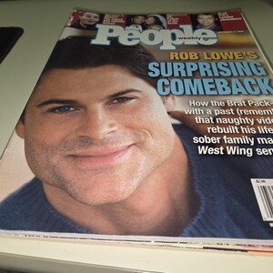Könnte beinhalten: Ein People Weekly Magazin-Cover mit einem großen Porträt von Rob Lowe in einem blauen Pullover. Die Schlagzeile lautet Rob Lowe's Surprising Comeback, mit zusätzlichem Text über sein Leben, seine Karriere und einem Barcode unten rechts.