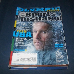 May include: Sports Illustrated Olympic Preview magazine featuring a portrait of Bode Miller on the cover. The text reads Olympic Preview, Sports Illustrated, Everything You Need To Know About Team USA, Next Stop: Russia, and The Cloud Over Putin's Games.
