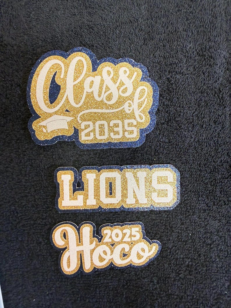 three stickers or patches with text and logos related to graduation or school events.