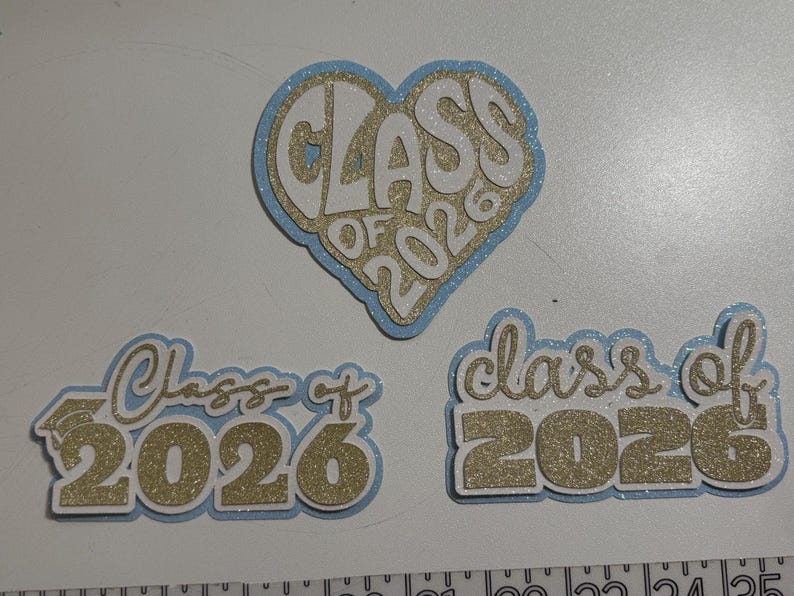 three glittery heart-shaped cutouts with the text "CLASS OF 2026" written on them, likely representing a graduation or class of 2026 event.