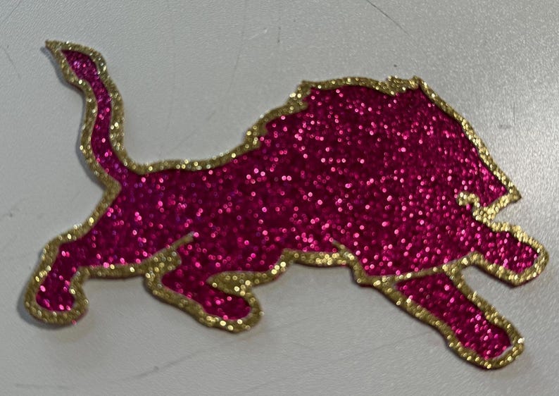 A pink glittery lion sticker or decal with a gold border.