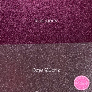 May include: Two horizontal sections of glittery material. The top section is a deep raspberry pink color with the text "Raspberry" centered. The bottom section is a muted rose quartz pink color with the text "Rose Quartz" and a circular logo.