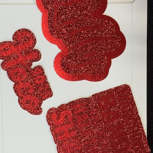 three red glittery objects, including a large red shape, a smaller red shape, and a rectangular red object.