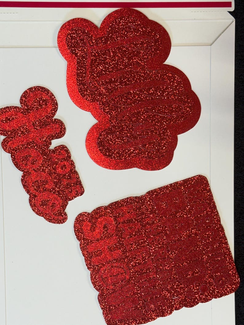 three red glittery objects, including a large red shape, a smaller red shape, and a rectangular red object.