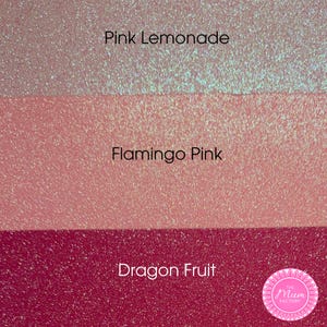 May include: Three horizontal bands of glittery material in varying shades of pink. The top band is labeled Pink Lemonade, the middle band is labeled Flamingo Pink, and the bottom band is labeled Dragon Fruit. A circular logo for The Mum Factory is visible.
