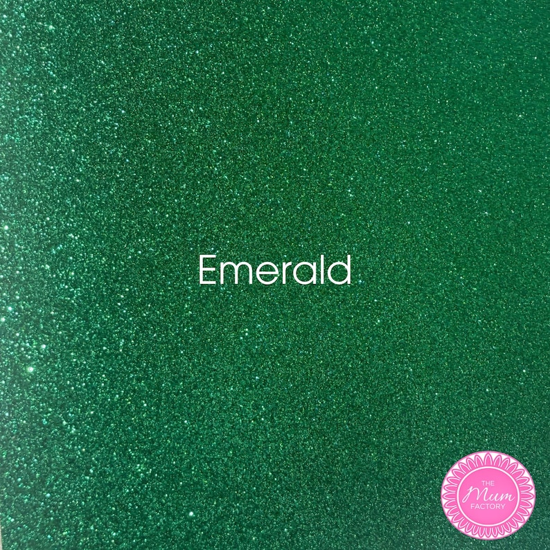 May include: A sheet of emerald green glitter material with a textured, sparkling surface. The word "Emerald" is printed in white in the center. A circular pink logo with the text "The Mum Factory" is located in the bottom right corner.