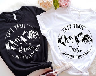 May include: Two black and white t-shirts with a mountain range graphic and the text "Last Trail" and either "Bride" or "Tribe" followed by "Before the Veil".