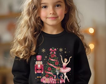 May include: Black sweatshirt featuring a Christmas-themed graphic. The design includes a nutcracker, Christmas tree, ballerina, and mouse prince. The graphic is in shades of pink, red, and gold. The word "black" is printed on the bottom left.