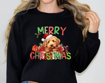 Può includere: Felpa nera con un design festivo che presenta un cane con un cappello di Babbo Natale e circondato da regali. Il testo "Merry Christmas" è scritto in lettere colorate.