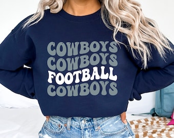 Op de afbeelding: Een marineblauw sweatshirt met de woorden "COWBOYS FOOTBALL COWBOYS" in een retro, wit en grijs lettertype.