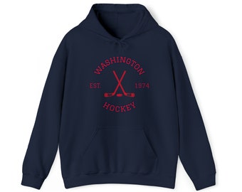 May include: A navy blue hoodie with a front pocket and a drawstring hood. The red graphic on the front reads "WASHINGTON HOCKEY EST. 1974" with crossed hockey sticks.