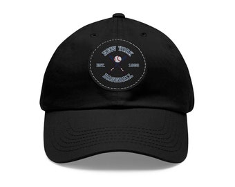 Peut inclure: Casquette de baseball noire avec une visière incurvée. Le chapeau présente un écusson circulaire avec le texte "NEW YORK BASEBALL EST. 1903" entourant une balle de baseball et des battes croisées en bleu et blanc.