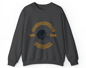May include: A dark gray sweatshirt with a gold embroidered logo that says "JACKSONVILLE EST. 1995 FOOTBALL" with a football helmet graphic.