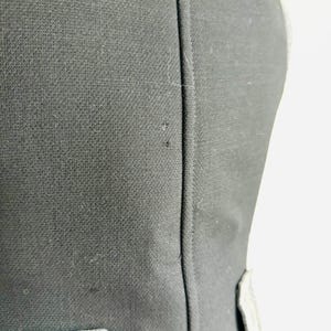 Puede incluir: Primer plano de una prenda negra con tejido texturizado. La prenda tiene una costura vertical en el centro y un acento de color claro cerca de la parte inferior. La tela parece ser un material tejido.