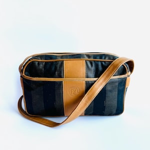 May include: A brown and black striped shoulder bag with a brown leather strap and a brown leather patch with the letter "F" in the center.
