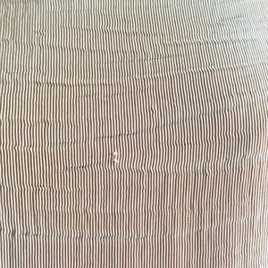 May include: Close-up of a fabric with a vertical striped pattern. The stripes alternate between a light beige and a darker brown color. The fabric has a slightly textured appearance, with subtle variations in the stripes.