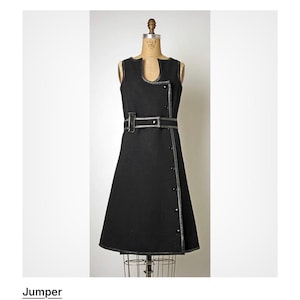 Puede incluir: Vestido negro sin mangas con un escote &uacute;nico y cintur&oacute;n a juego. El vestido presenta ribetes plateados y botones. El vestido se exhibe en un maniqu&iacute;. De la d&eacute;cada de 1960.