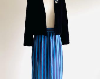 May include: A black velvet cropped jacket with a blue and white striped skirt. The jacket has a shawl collar and three-quarter sleeves. The skirt is knee-length and has a high waist.