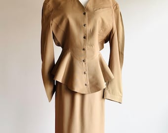 May include: A brown skirt suit with a fitted skirt and a peplum top with a button-up front.