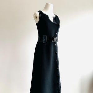 Puede incluir: Vestido negro sin mangas con cintur&oacute;n a juego y detalles de botones. El vestido tiene un escote &uacute;nico y se exhibe en un maniqu&iacute;. El vestido mide aproximadamente 140 cm de largo.