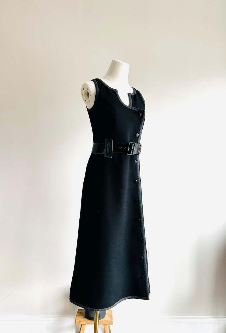 Puede incluir: Vestido negro sin mangas con cintur&oacute;n a juego y detalles de botones. El vestido tiene un escote &uacute;nico y se exhibe en un maniqu&iacute;. El vestido mide aproximadamente 140 cm de largo.