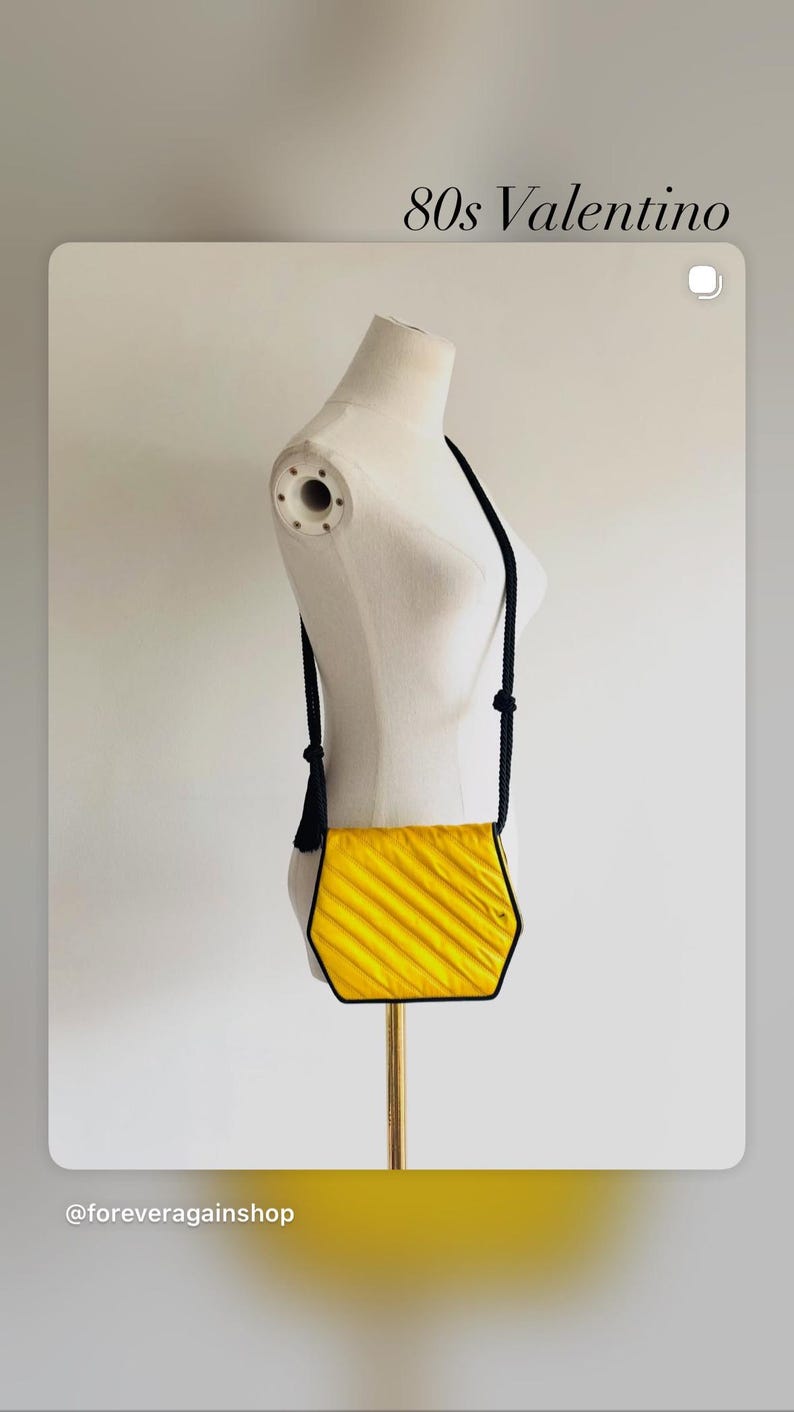May include: A vintage yellow Valentino crossbody bag with a black trim and strap. The bag has a textured, pleated design and a black tassel. The text "80s Valentino" is visible.