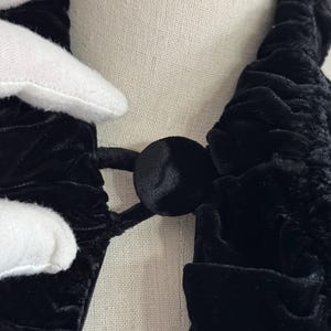 K&ouml;nnte beinhalten: Schwarzer Samt-Choker mit R&uuml;schen-Design und schwarzem Knopfverschluss.