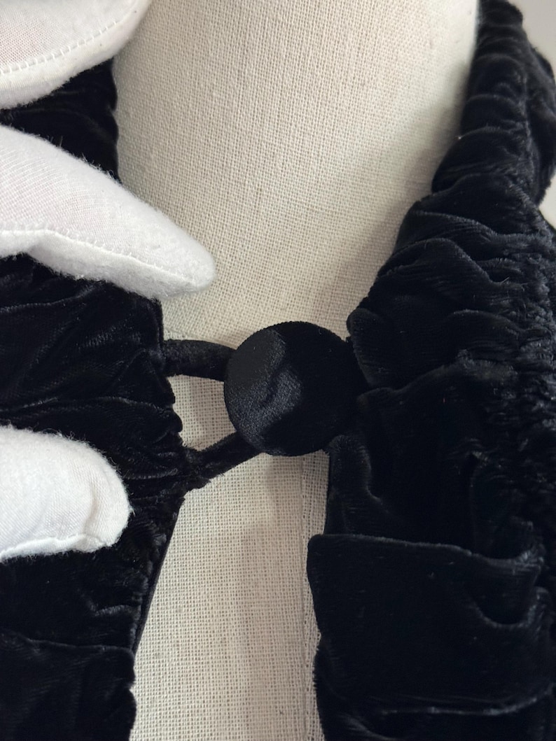 K&ouml;nnte beinhalten: Schwarzer Samt-Choker mit R&uuml;schen-Design und schwarzem Knopfverschluss.