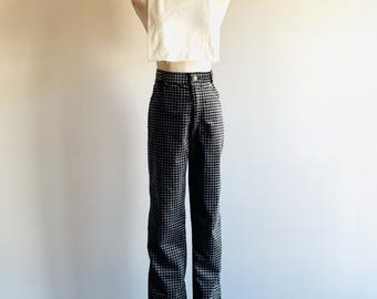 Könnte beinhalten: Ein cremefarbenes Rollkragen-Crop-Top und eine hoch taillierte, schwarz-weiß karierte Hose werden auf einer Schaufensterpuppe präsentiert. Die Hose hat ein ausgestelltes Bein. Das Outfit steht vor einer schlichten, hellen Wand.