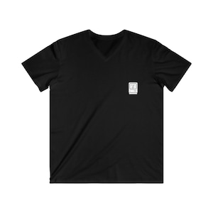 May include: Black V-neck t-shirt with a white graphic of a vintage computer on the left chest. The graphic features a smiling computer face. The shirt is made of a soft material.