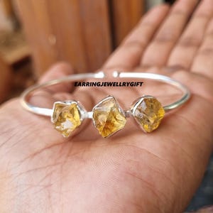 Op de afbeelding: Zilveren armband met drie gele citrien edelstenen. De armband is open en verstelbaar.