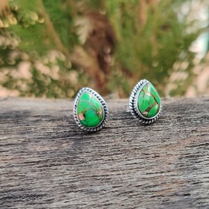 May include: A pair of silver teardrop earrings with green turquoise stones.