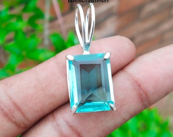 May include: A silver pendant with a light blue gemstone. The gemstone is cut in a rectangular shape with beveled edges.