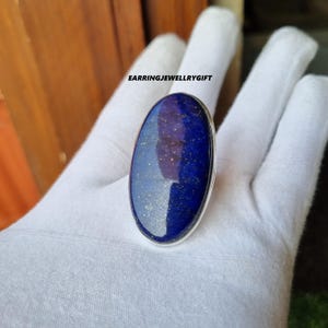 Peut inclure: Bague ovale en lapis-lazuli sertie d'argent sterling. La bague présente une pierre bleu foncé avec des reflets dorés.