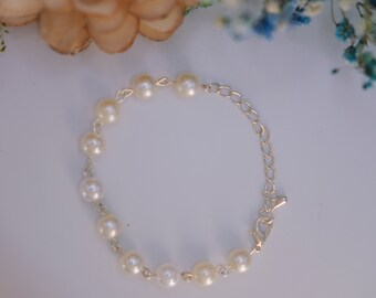 May include: A white pearl bracelet with a silver chain and clasp.