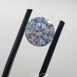 May include: A clear round gemstone with a faceted cut, held by black tweezers. The gemstone has a rainbow iridescent effect.